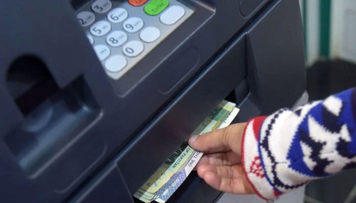An individual withdraws money from an ATM in Islamabad. — AFP/File
