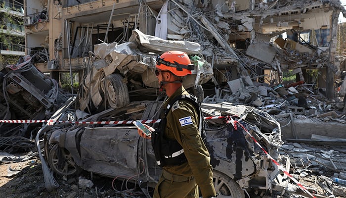 Rescue personnel walks past damaged vehicles at an impact site following missile attack from Iran on Israel, in Ramat Gan, Israel, June 14, 2025. — Reuters